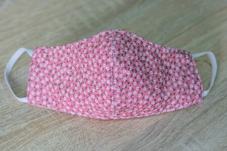 Handmade face masks made from cloth placed pink on wooden table, washable and reusable, can be used during shortage of surgical mask due to coronavirus pandemic. virus covid-19.の写真素材