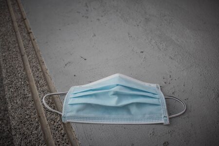 Blue disposable medical mask is on the road surface, on street. to prevent the Virus Covid-19....