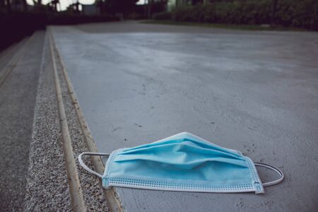 Blue disposable medical mask is on the road surface, on street. to prevent the Virus Covid-19. Concept viruses spread throughout the world. Do not throw away your used face mask. selective fofus. copy space.の写真素材