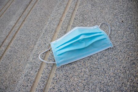 Blue disposable medical mask is on the road surface, on street. to prevent the Virus Covid-19. Concept viruses spread throughout the world. Do not throw away your used face mask. selective fofus. copy space.の写真素材