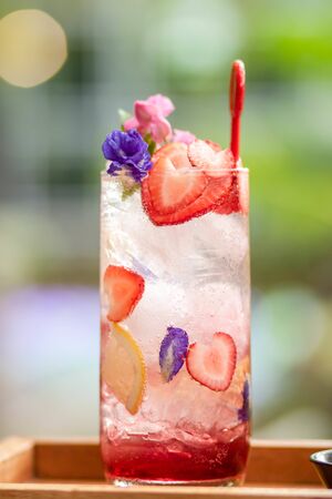Ice with sweet water topped with Fresh pink lemonade with raspberries decorated with mint leaves, orange suitable for summer. Strawberry mojito cocktail. a green natural background. candy summer .の写真素材