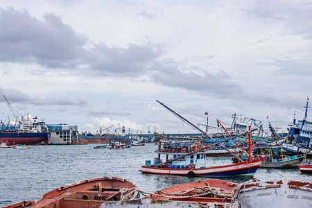 Chon buri,THAILAND-JULY 9,2020 : Fishing boat and fisherma in Thailand at Laemchabang Port in Thailand. Wooden boats. Old boat moored.Overcast sky.のeditorial素材