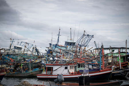 Chon buri,THAILAND-JULY 9,2020 : Fishing boat and fisherma in Thailand at Laemchabang Port in Thailand. Wooden boats. Old boat moored.Overcast sky.のeditorial素材