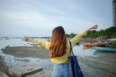 Happy woman standing arms outstretched back and enjoy life on the beach at Sea. sea along the coast...