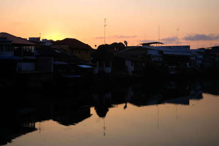 Photos of the riverside community at Bridge in Chanthaburi, Thailand. In the evening sunset And there is a shadow hitting the water surface.の写真素材