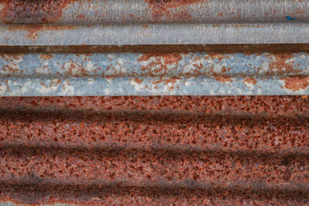 Sharp edges of the rusty metal sheets placed on the floor. Old aged weathered rusty galvanized corrugated iron sheet roof of abandoned mood. selective focus blur background. Vintage.with copy space and space for text.の写真素材