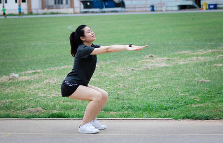 Young woman has an outdoor workout at the park. She is stretching her arms and looking away. Health...