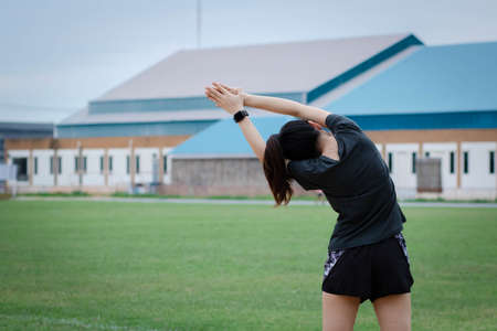 Young woman has an outdoor workout at the park. She is stretching her arms and looking away. Health care,の写真素材