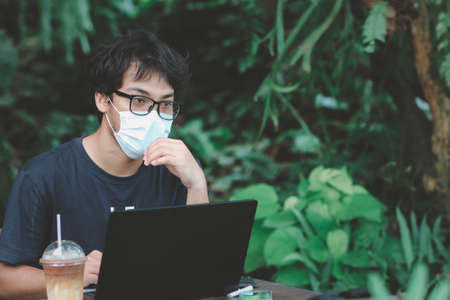 multitasking man using tablet, Laptop on wooden desk with iced coffee in the cafe.の写真素材