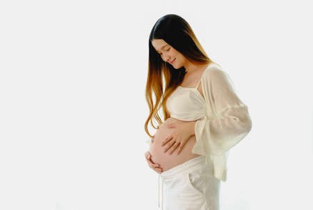 Young beautiful pregnant woman standing of happy pregnant woman with big belly at window. Smiling...