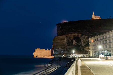 Etretat, Normandy, France - The cliff at the north ('Amont' cliff) with its natural arch and  the church, by nightの写真素材