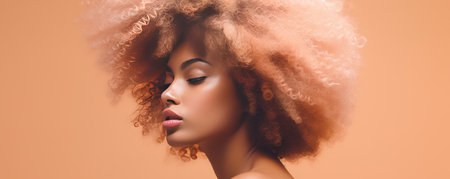 Intimate Close Up of a Black Woman Showcasing a Peach Fuzz Colored Afro Against a Soft Peach Studio Backdropの素材