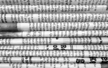 A black and white background of English language newspapers stacked and folded in a horizontal position and viewed in close upの写真素材