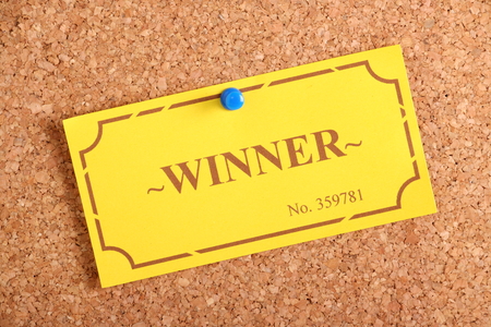 The winning golden raffle or lottery ticket pinned to a cork notice board as a concept for being a winner or achiever の写真素材