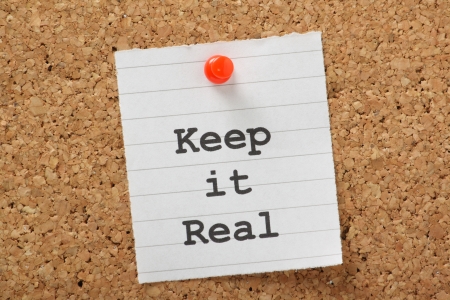 The phrase Keep It Real typed on a piece of lined paper and pinned to a cork notice boardの写真素材