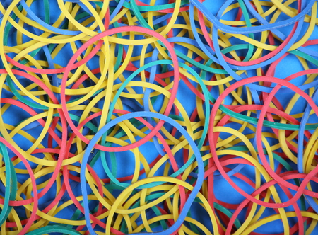 Multicolored rubber or elastic bands scattered on blue paper to provide a colorful の写真素材