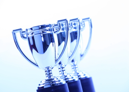 Toy Silver Trophy Cups in a Row with a cool blue light effectの写真素材