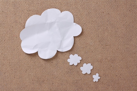 A blank white paper thought or think bubble arranged as a collage on a textured background の写真素材