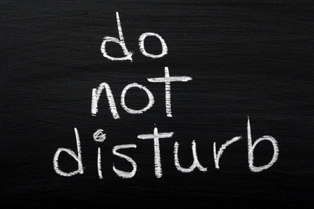 Do Not Disturb written by hand in white chalk on a used blackboardの写真素材