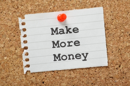 The phrase Make More Money typed on a piece of note paper and pinned to a cork notice boardの写真素材