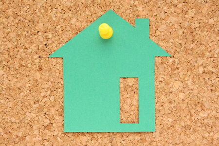 Post it note in the shape of a green house, pinned to a cork boardの写真素材