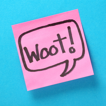 The word Woot written inside a speech bubble on pink sticky note attached to a blue paper background...