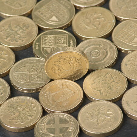 British Pound Coins on a black slate background with focus on the coin standing on edge in the...