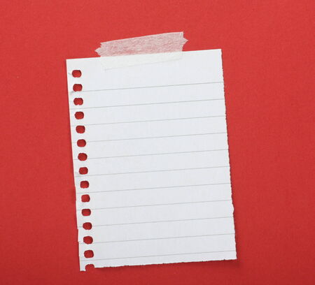 Piece of lined paper taped to a red background with copy space の写真素材