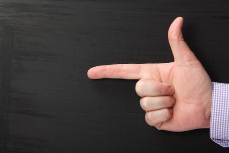 Male hand in a business shirt with the index finger pointing at a blank space on a used blackboardの写真素材
