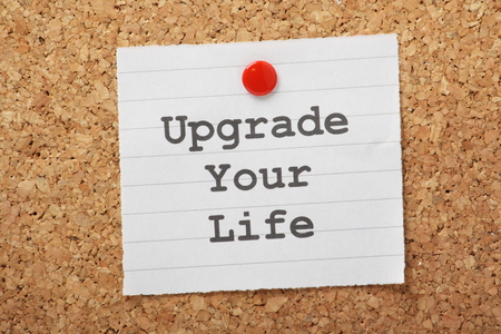 The phrase Upgrade Your Life typed on a piece of paper and pinned to a cork notice boardの写真素材