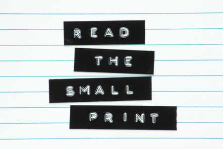 A warning to read the small print, made from embossed letters on plastic adhesive labels fixed to lined paper の写真素材