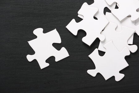A pile of blank white jigsaw pieces on a used blackboard