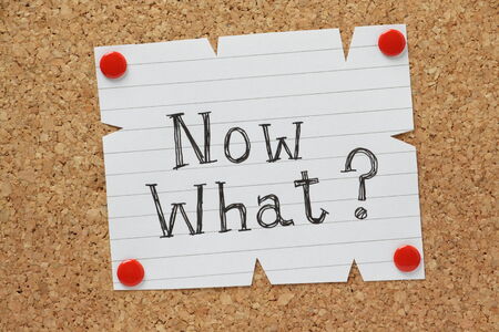 The question Now What  written by hand on a piece of paper pinned to a cork notice boardの写真素材