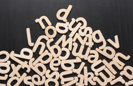 Random wooden letters piled up on a blackboard surface
