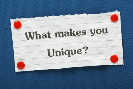 The question What Makes You Unique? typed on a piece of lined paper and pinned to a blue notice...