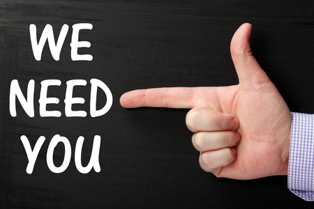 Male hand wearing a business shirt pointing at the phrase We Need You written on a blackboardの写真素材