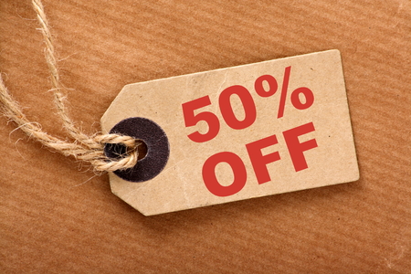 Fifty percent off announcement message in red text on a brown paper price tag and wrapping paper with stringの写真素材