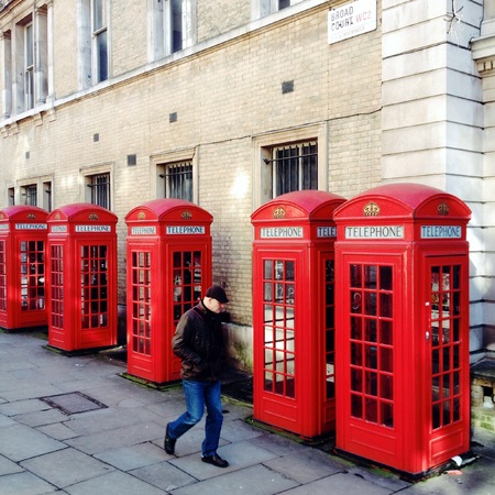 London, United Kingdom - February 17th, 2015: A man walks by five red telephone boxes in Central London, England. The K2 type kiosk was designed by British architect Sir Giles Gilbert Scott and introduced in 1926のeditorial素材