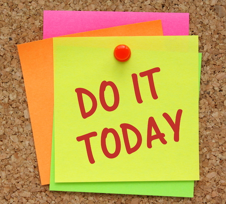 The phrase Do It Today on a yellow sticky note pinned to a cork notice board as a reminderの写真素材