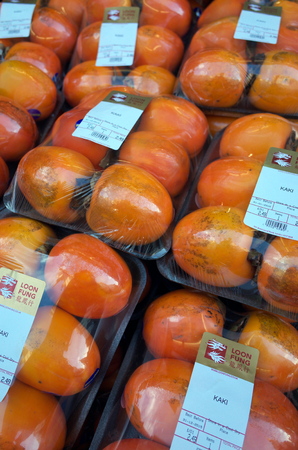 London, England - December 28, 2015: Persimmon or Kaki fruit on display in cartons outside the Loon Fung supermarket in Chinatown, London, Englandのeditorial素材