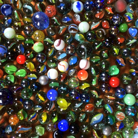 Background of round glass playing marbles in various styles and colors on a flat surfaceの写真素材