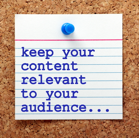 The phrase Keep Your Content Relevant to Your Audience in blue text on a note card pinned to a cork notice board as a reminder for your social media marketing strategyの写真素材