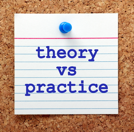 The words Theory vs Practice in blue text on a note card pinned to a cork notice board as a reminderの写真素材