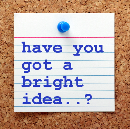 The words Have You Got A Bright Idea? in blue text on a note card pined to a cork notice boardの写真素材