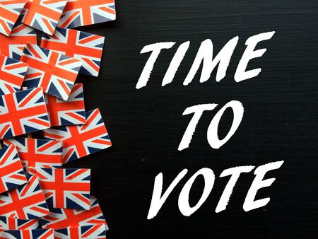 The words Time To Vote in white text on a blackboard next to Union Jack flags as a reminder to vote in the United Kingdom General Electionの写真素材