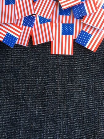 Miniature paper flags of the United States of America on a blue denim material background with copy spaceの写真素材