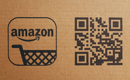 Bracknell, England - February 10, 2018: Close up of the Amazon company shopping trolley logo next to a QR or Quick Response bar code on brown cardboard packaging. Photographed in Bracknell, Englandのeditorial素材