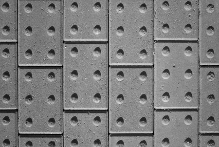 Tactile paving bricks with shadow detail photographed and processed in black and white to provide an abstract backgroundの写真素材