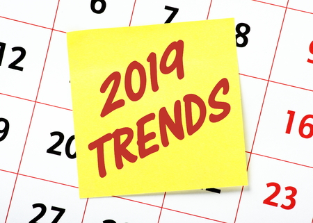 The words 2019 Trends written on a yellow sticky note and posted on a wall calendarの写真素材