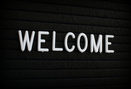 The word Welcome in white plastic letters on a black letter boardの写真素材